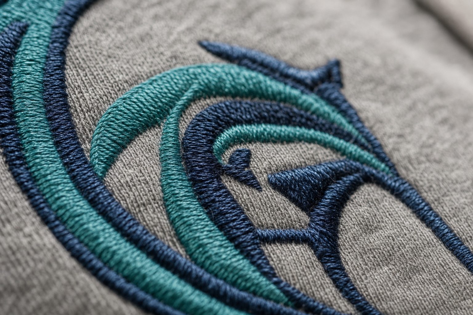 Close-up of teal and navy embroidery stitching on gray fabric